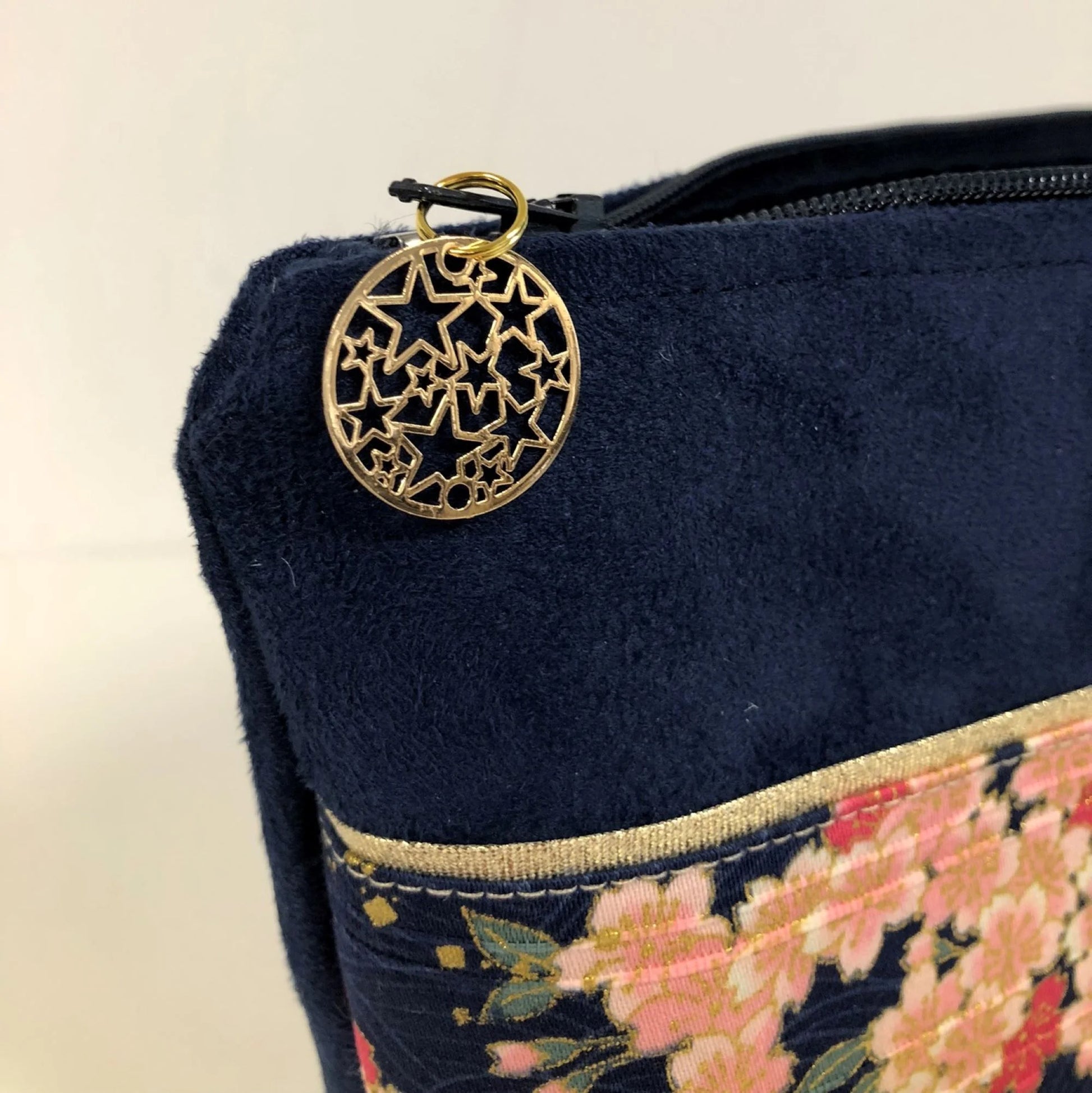 La fermeture éclair de la pochette à maquillage bleu marine en tissu japonais fleurs de cerisier.