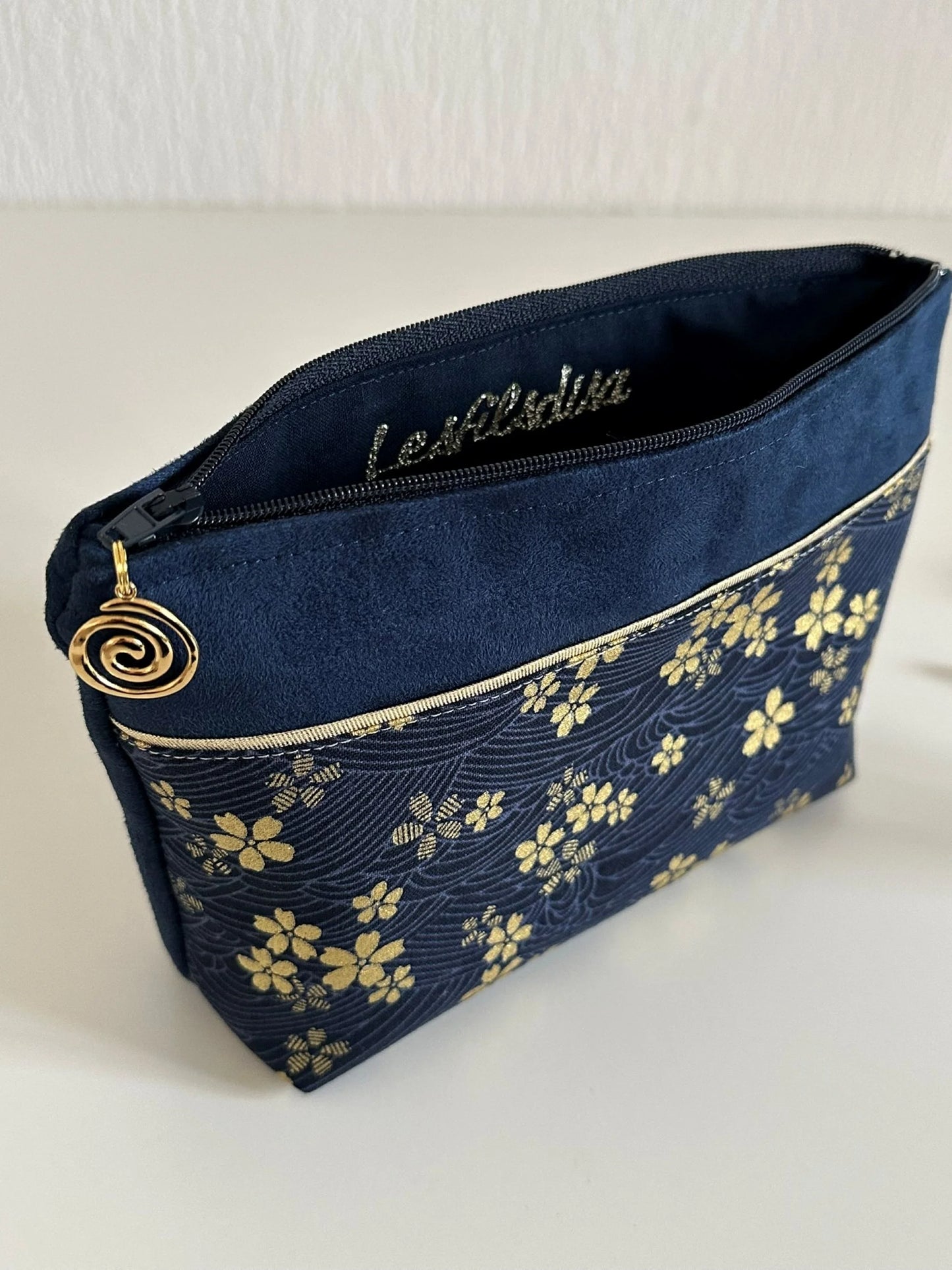 Aperçu de la doublure intérieure de la pochette à maquillage fleurie bleu et dorée.