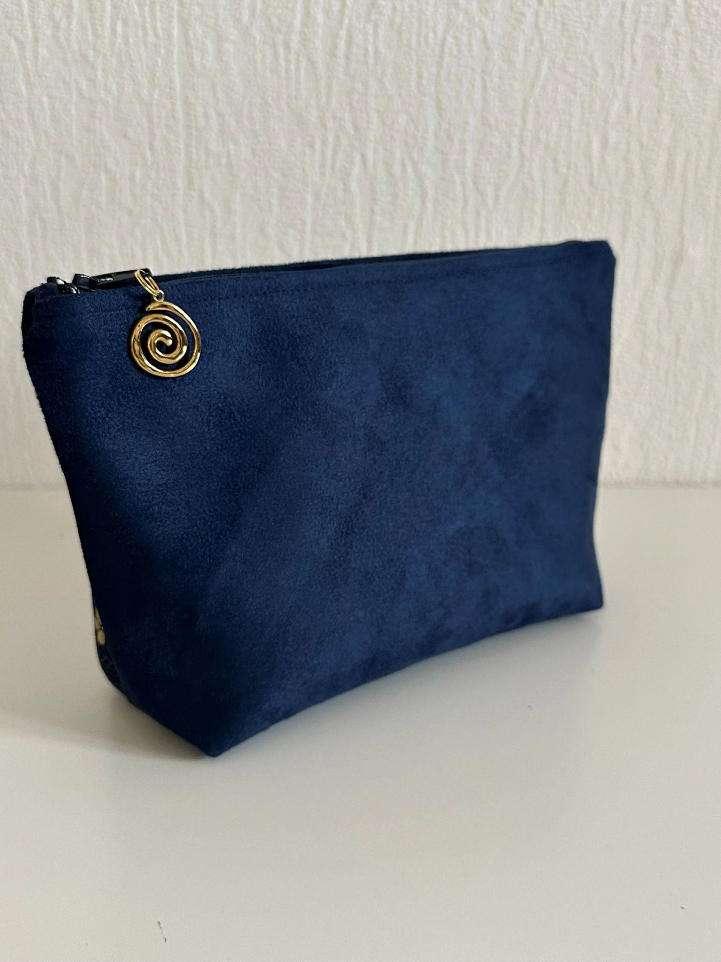 Le dos de la pochette à maquillage fleurie bleu et dorée.