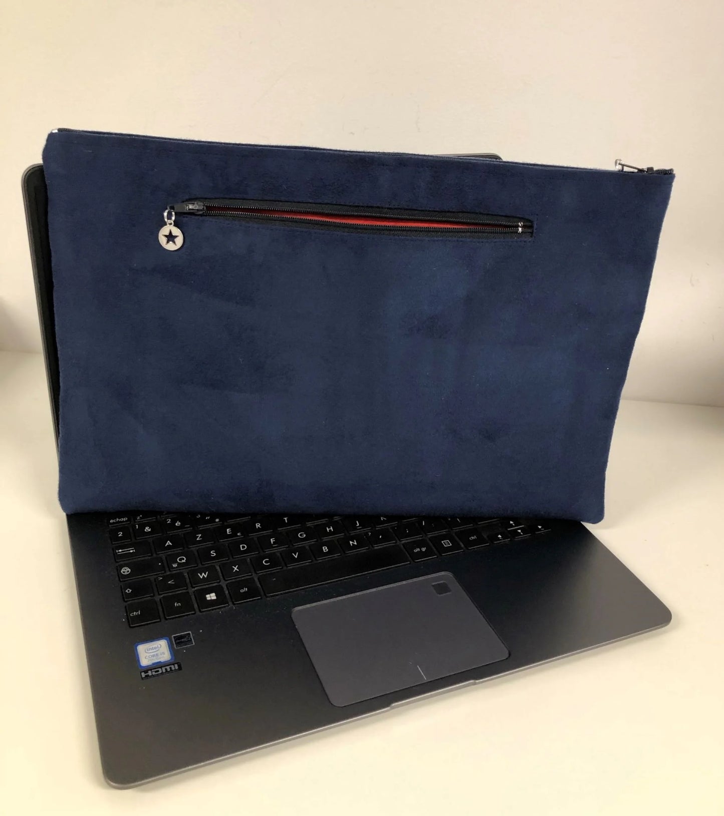 La pochette ordinateur bleu marine et argentée aspect reptile, avec poche chargeur à l'arrière.