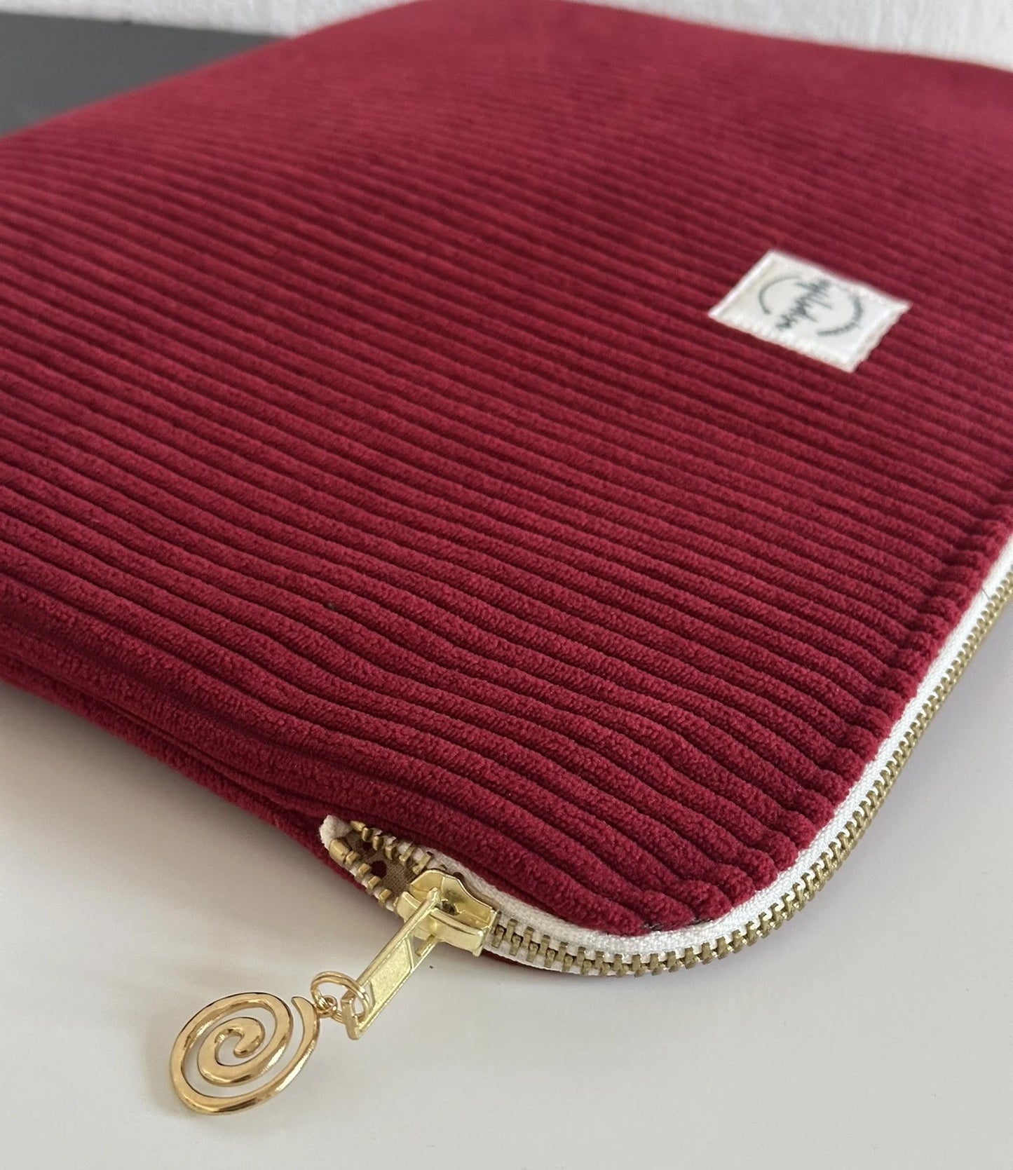 Aperçu de l'ouverture élargie de la pochette ordinateur en velours cotelé bordeaux.