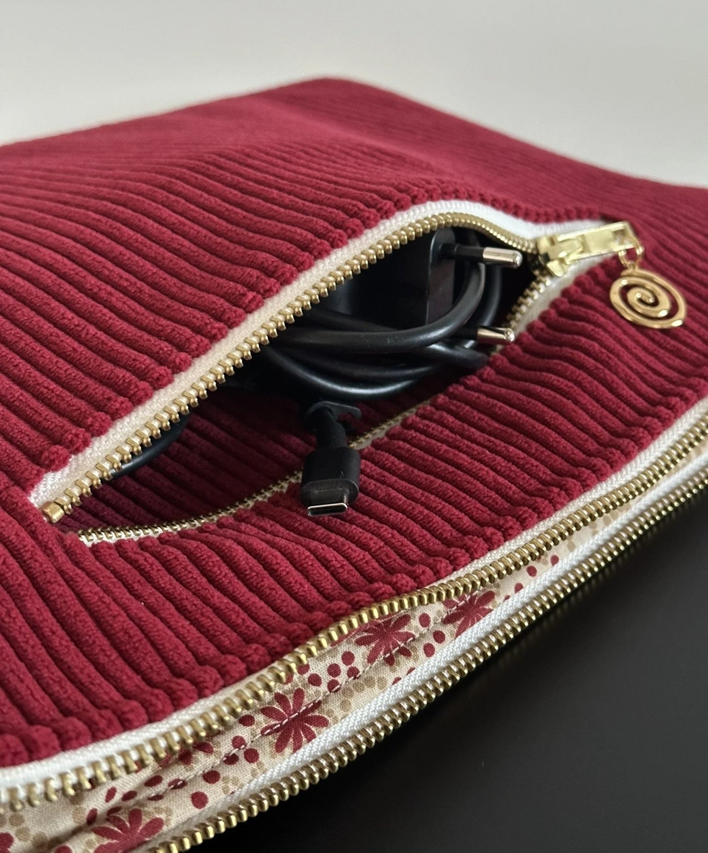 Vue détaillée de la poche chargeur zippée de la pochette ordinateur en velours cotelé bordeaux.