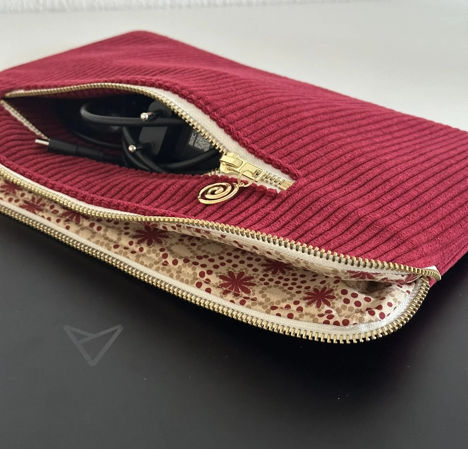 La doublure intérieure assortie de la pochette ordinateur en velours cotelé bordeaux.