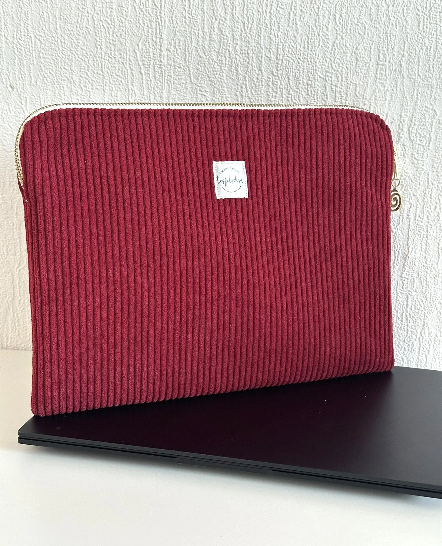 La pochette ordinateur en velours cotelé bordeaux, face avant.