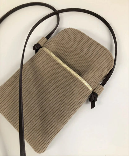 La pochette téléphone bandoulière en velours cotelé beige et cuir marron.