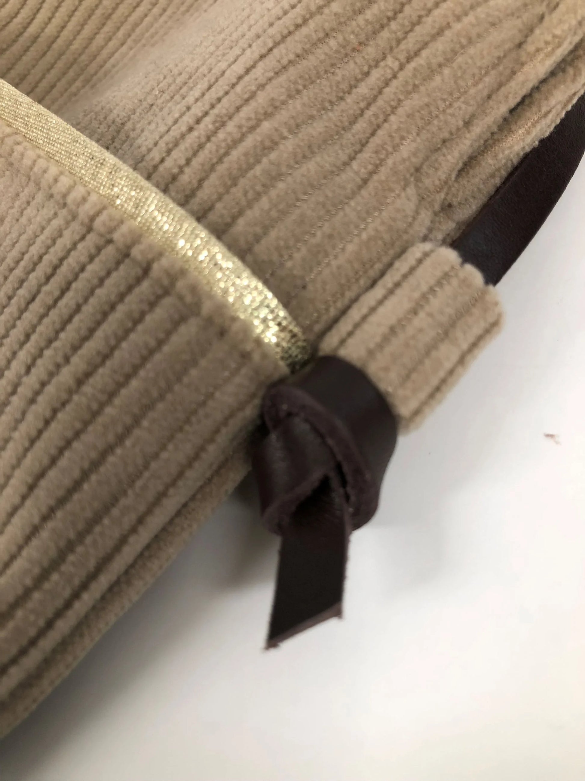 Vue détaillée de la lanière en cuir  nouée de la pochette téléphone bandoulière en velours cotelé beige.