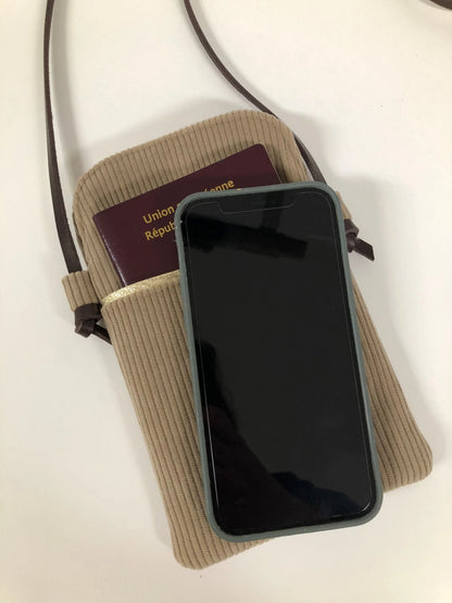 Téléphone et passeport avec la pochette téléphone bandoulière en velours cotelé beige.