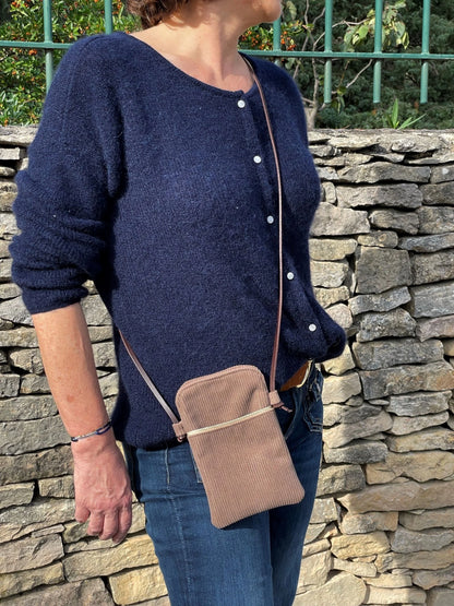 La pochette téléphone bandoulière en velours cotelé beige portée en travers.