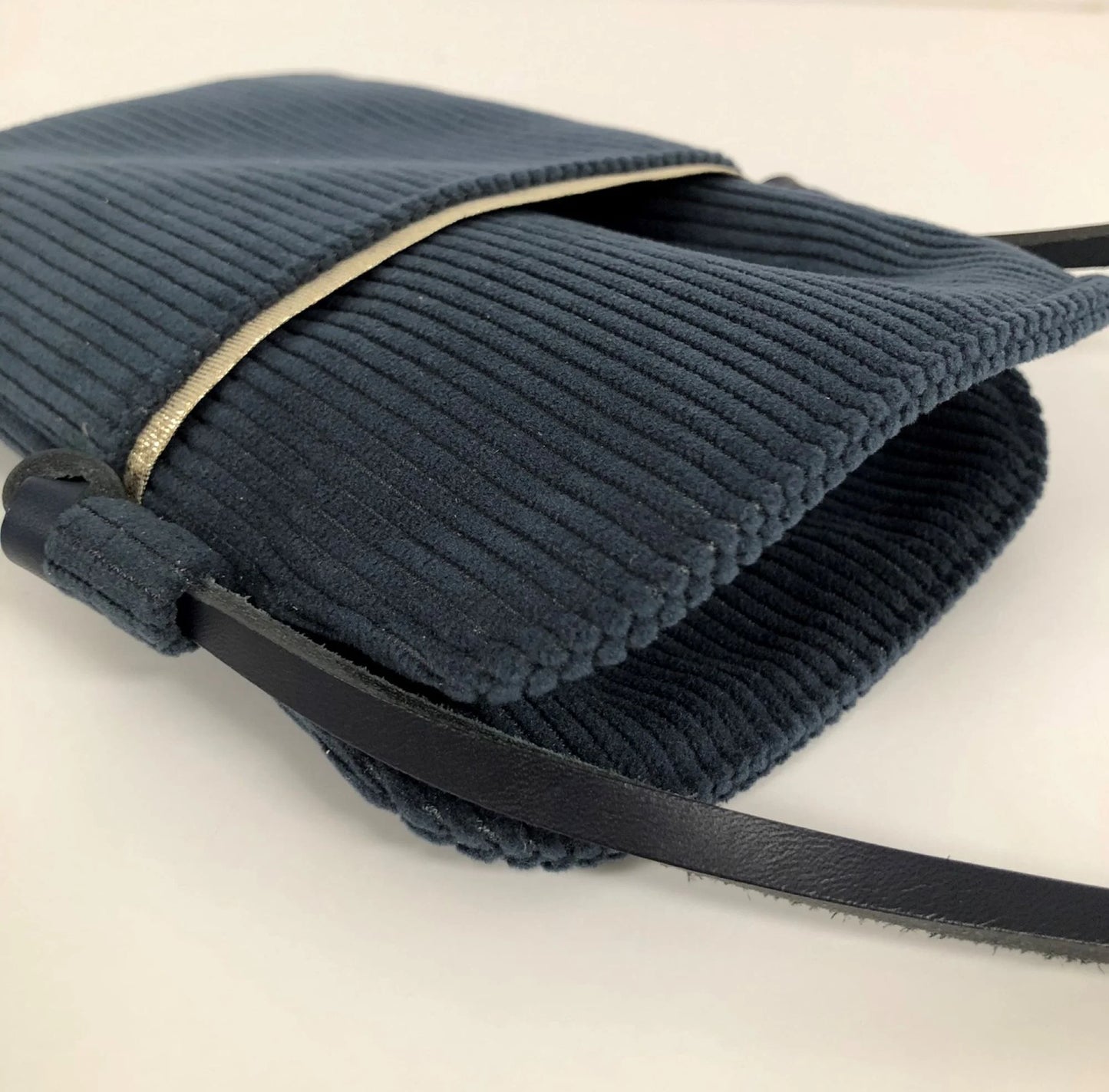 La pochette téléphone bandoulière en velours cotelé bleu canard et cuir noir.