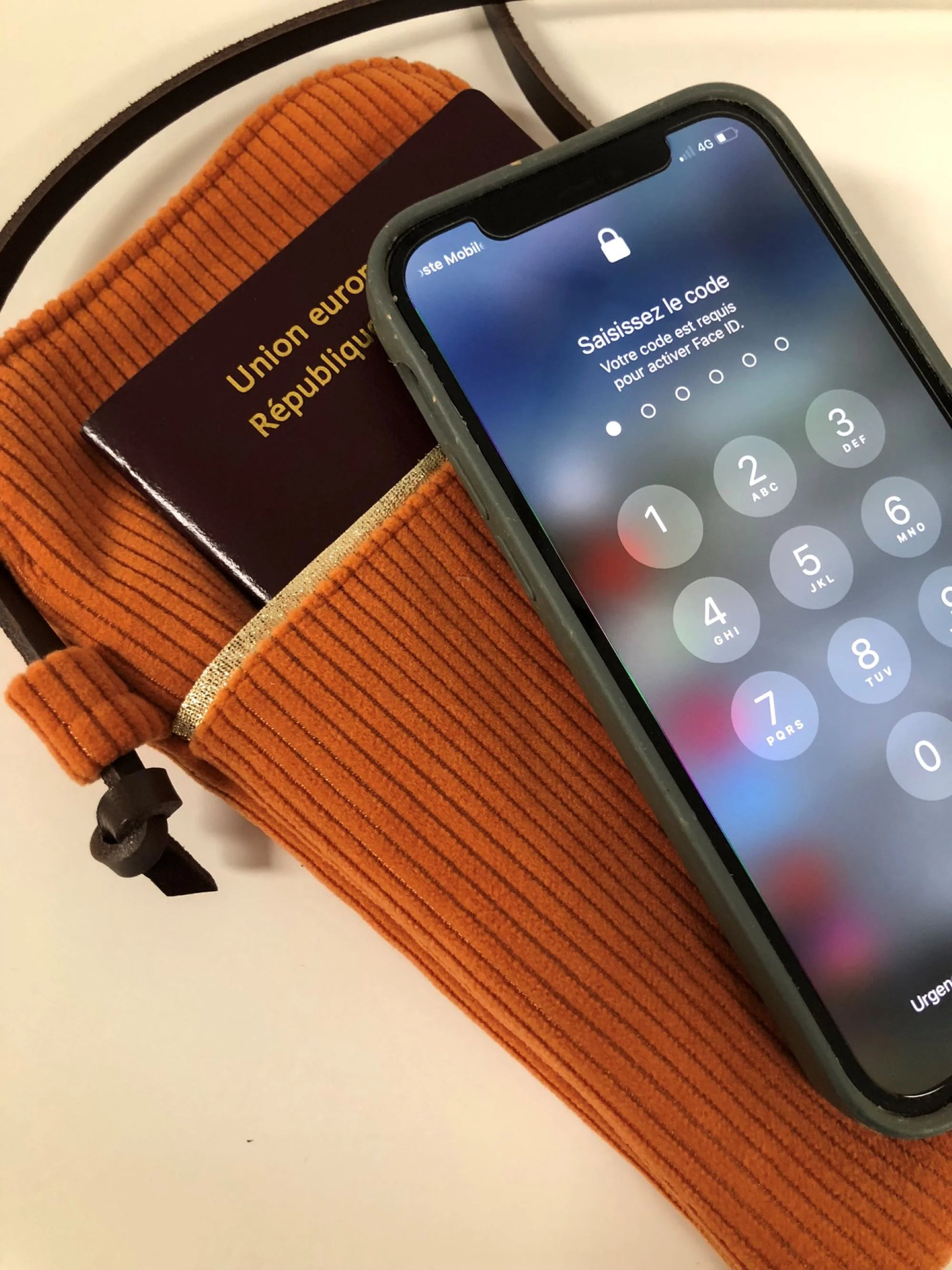 Passeport et téléphone avec la pochette téléphone bandoulière en velours cotelé orange.