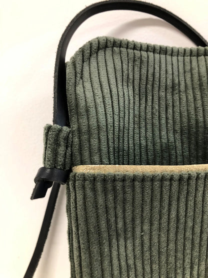 La lanière en cuir marron nouée de la pochette téléphone bandoulière en velours cotelé vert kaki .