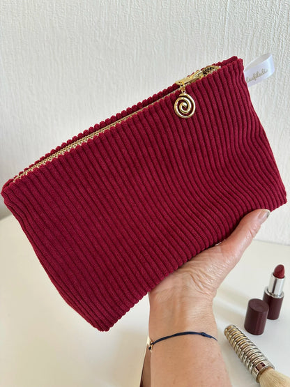 la pochette en velours cotelé bordeaux tenu en main