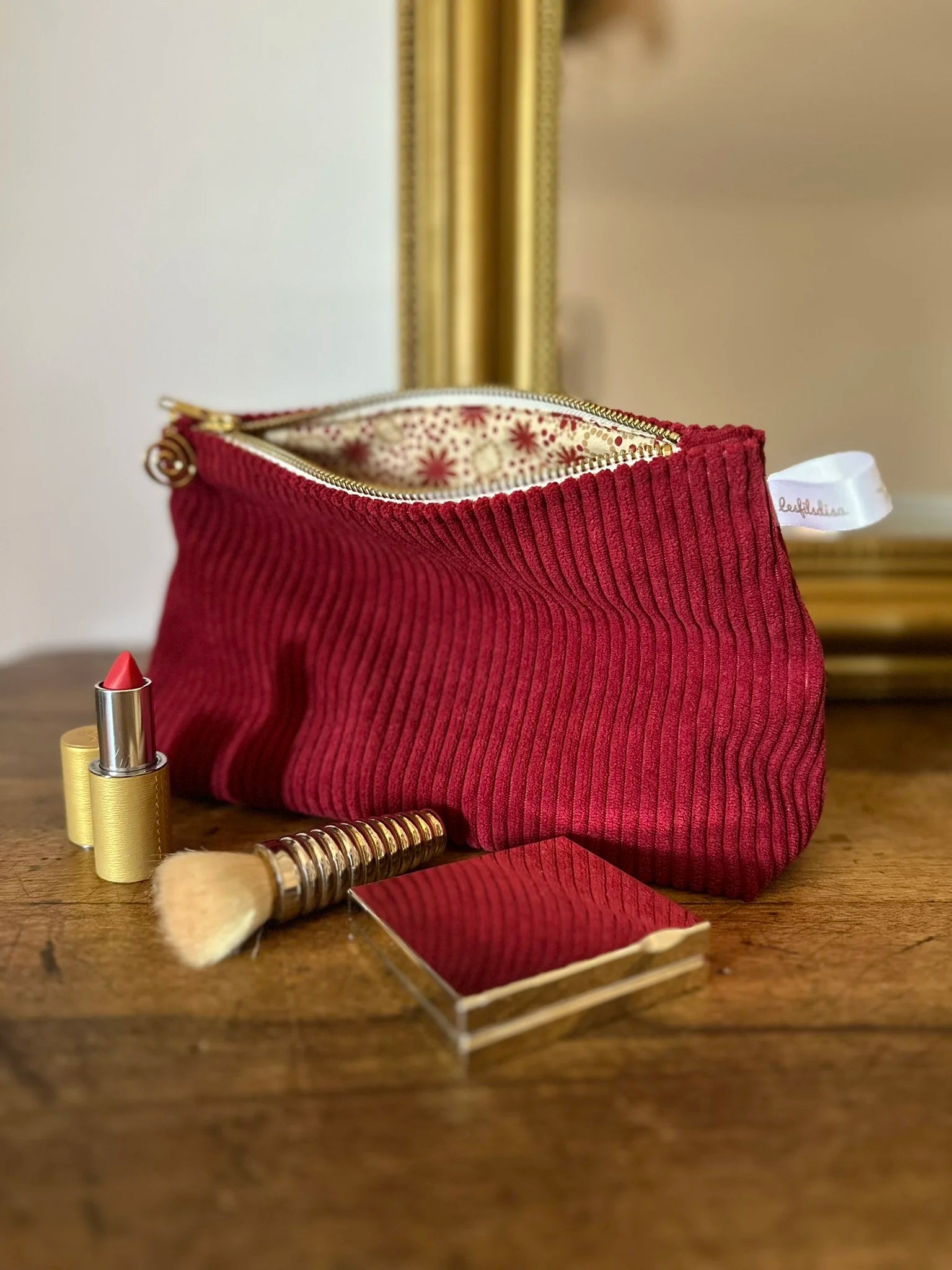 La pochette en velours cotelé bordeaux avec maquillage.