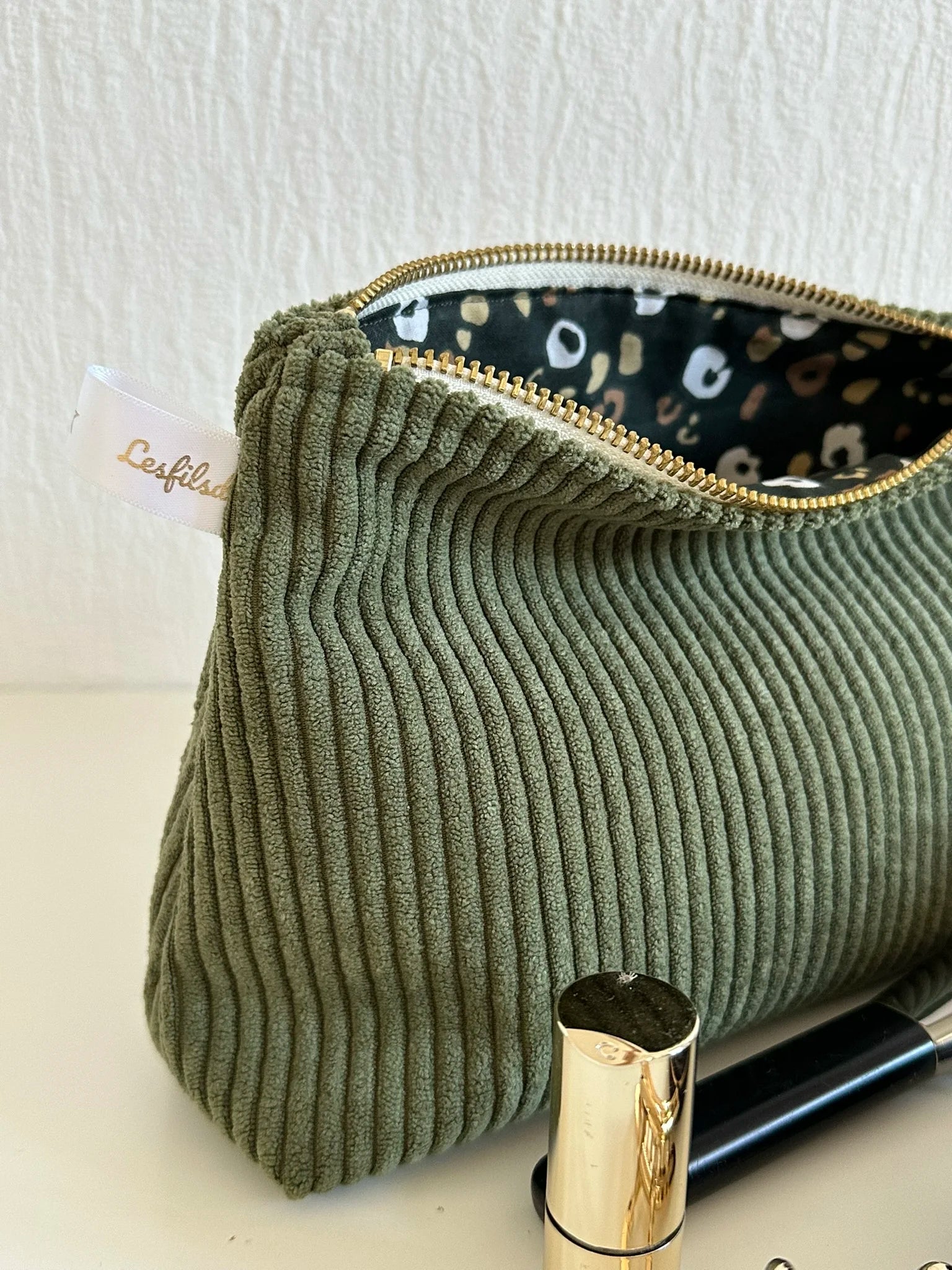 La fermeture métal doré de la pochette en velours côtelé vert armée.