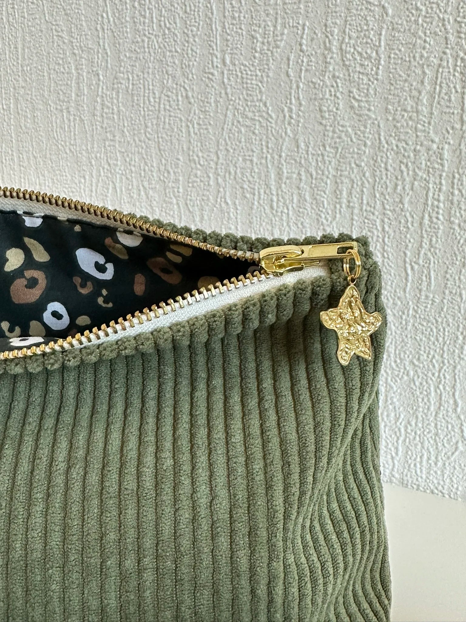 La breloque dorée de la pochette en velours côtelé vert armée.