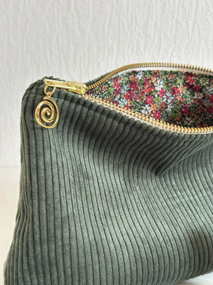 La breloque dorée de la pochette en velours côtelé vert kaki.