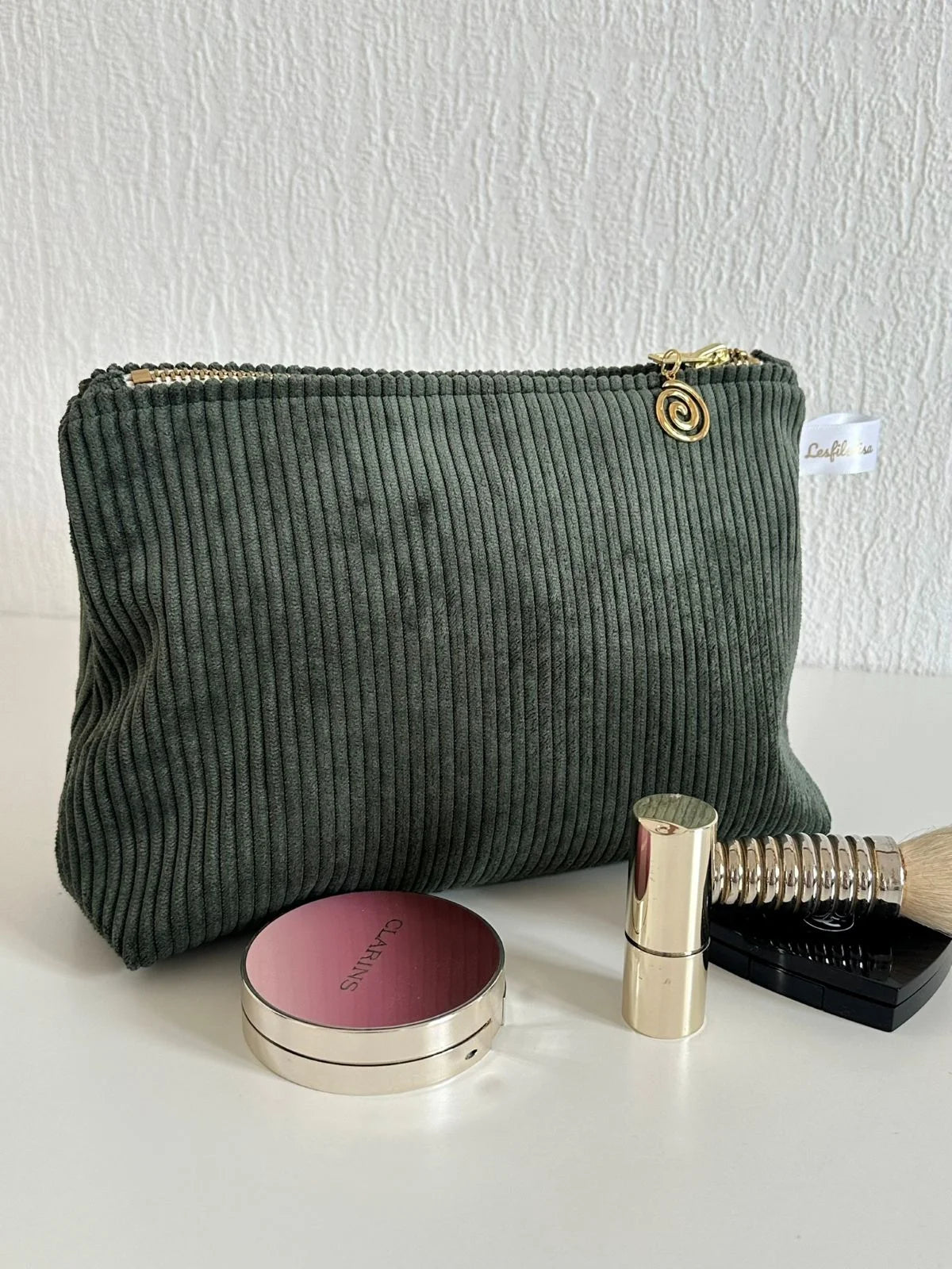 La pochette en velours côtelé vert kaki, fermée.