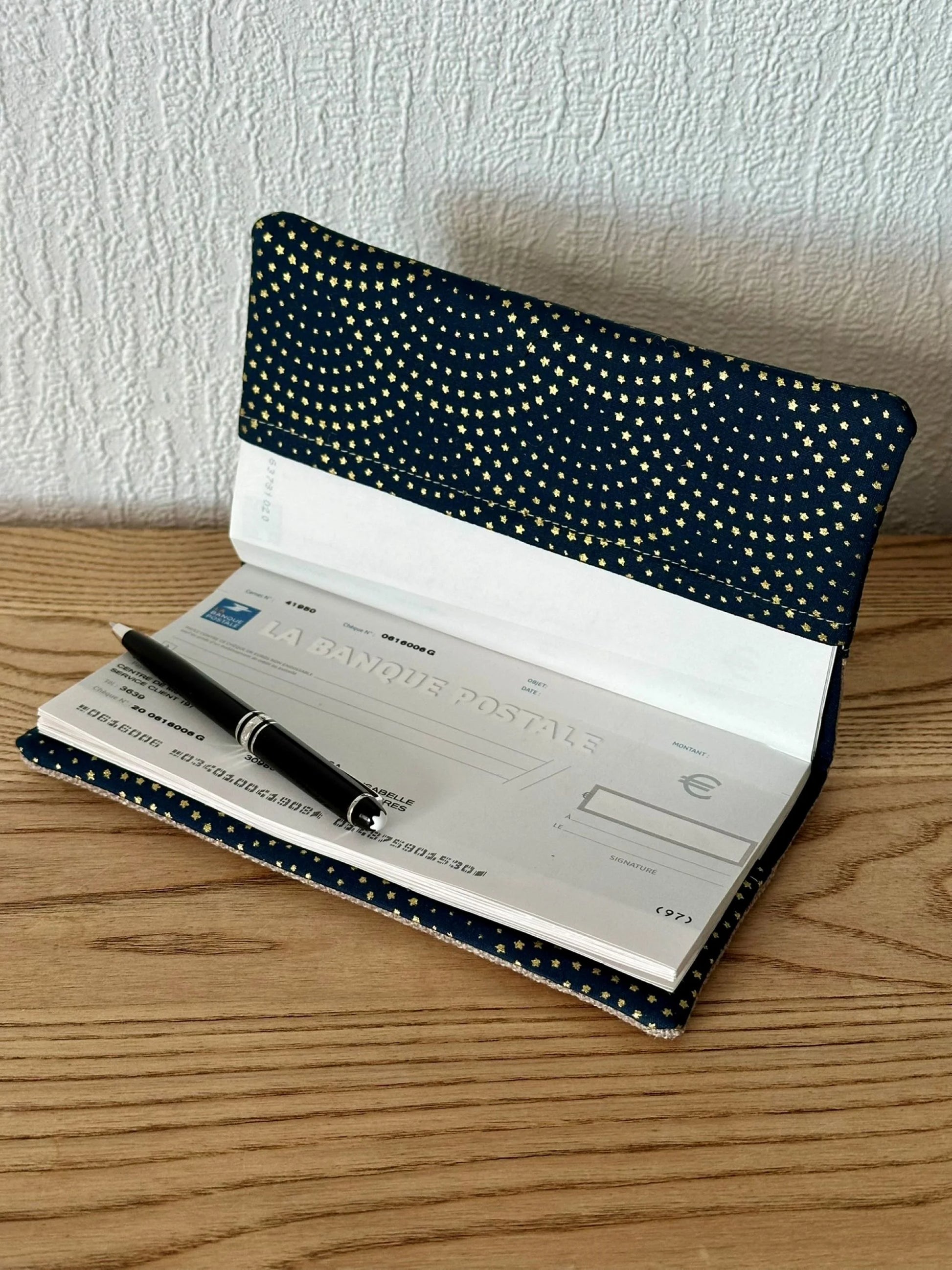 Le porte chéquier beige et bleu à étoiles dorées, ouvert.