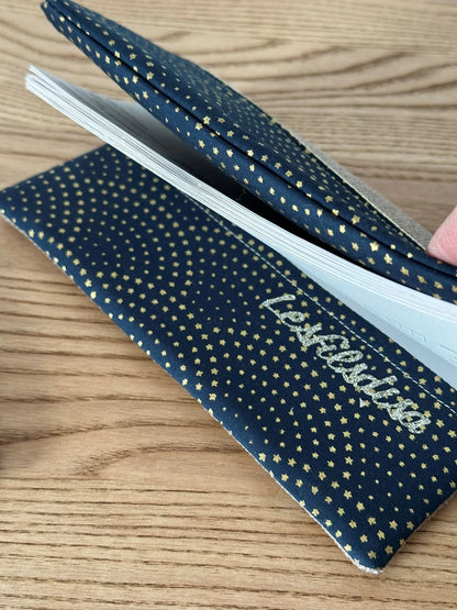 Le rabat inférieur du porte chéquier beige et bleu à étoiles dorées.