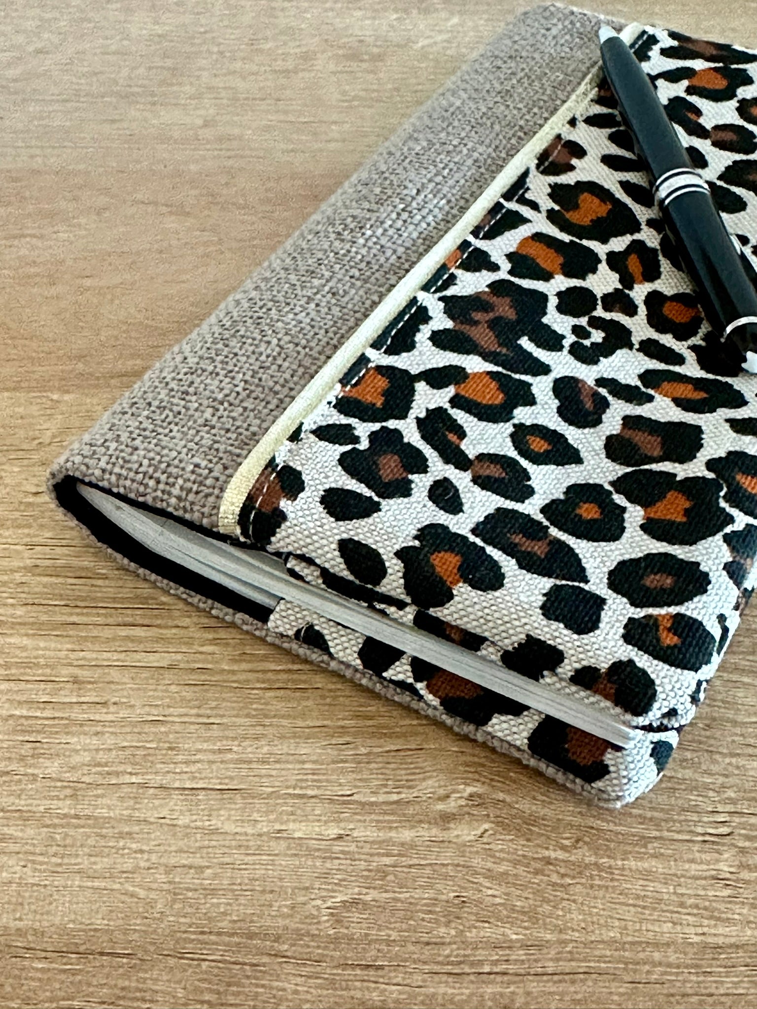 Vue latérale du porte-chéquier léopard en lin beige.