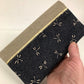 Le porte chéquier en lin beige et tissu japonais bleu libellules tenu en main