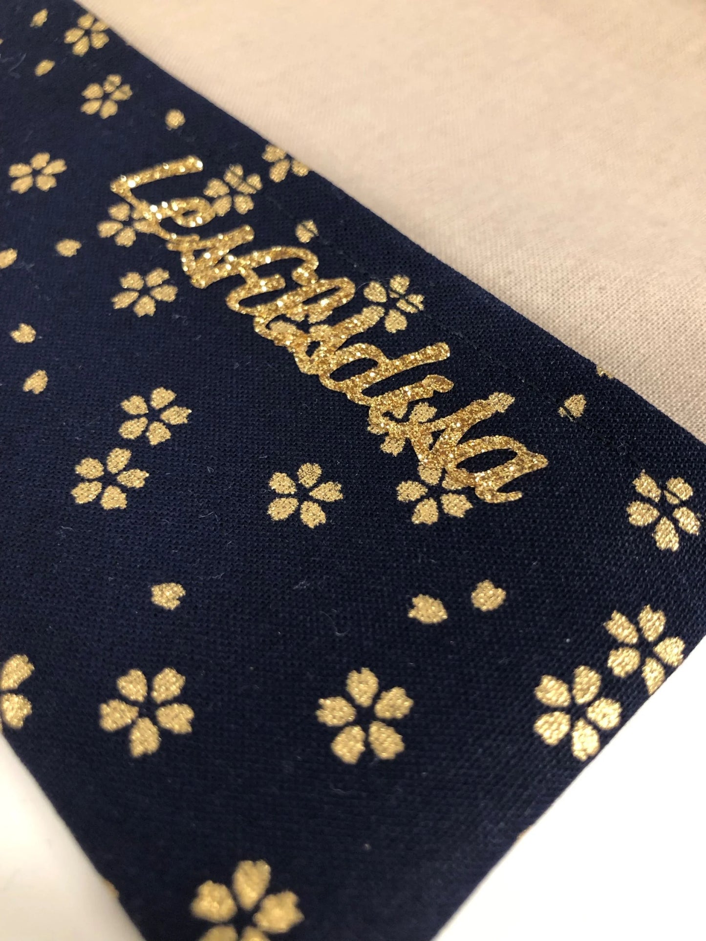 La marque Lesfilsdisa apposée sur le rabat inférieur du porte-chéquier en lin beige et tissu japonais Sakura bleu nuit.