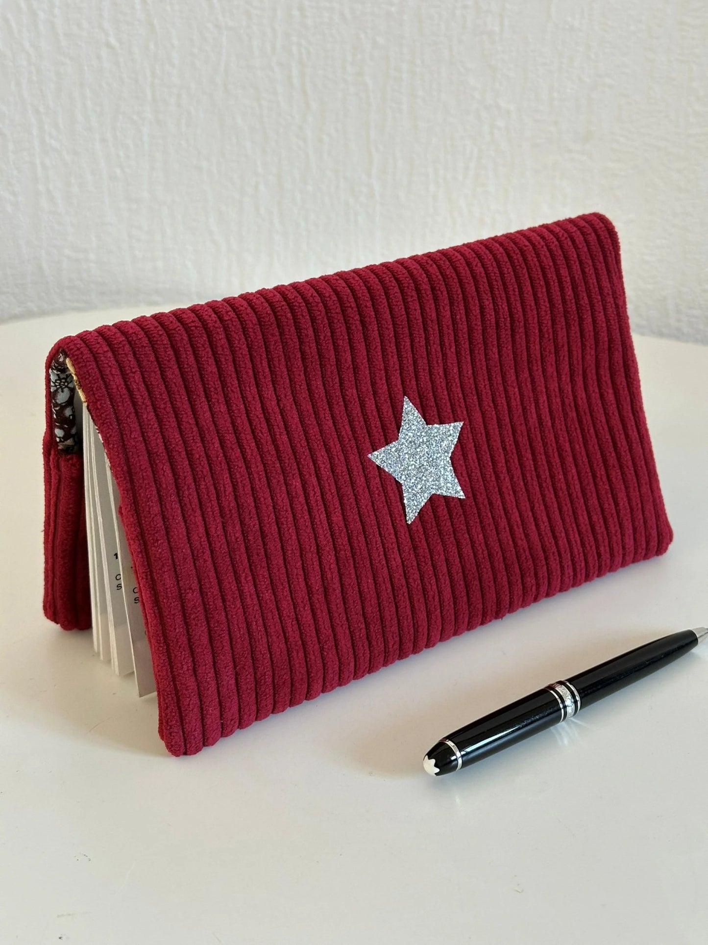 Le porte chéquier en velours bordeaux avec étoile pailletée argentée en face avant.