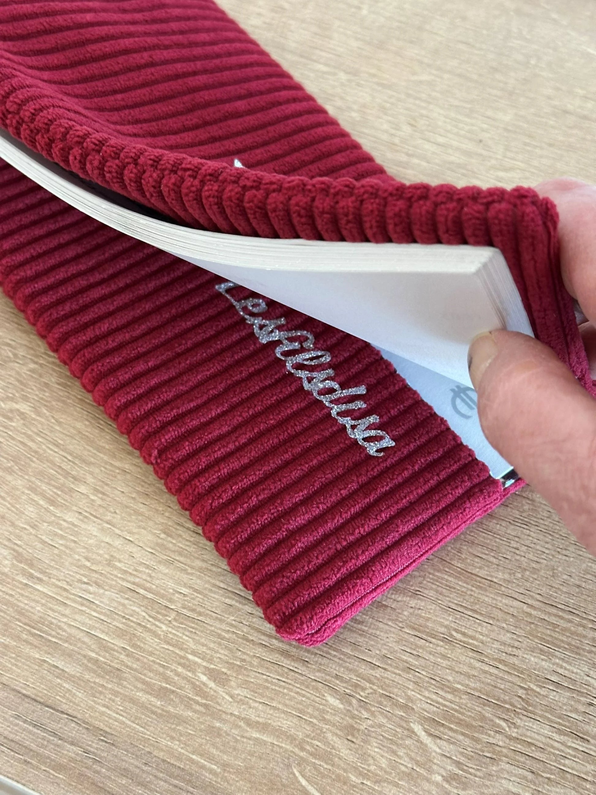 Le rabat inférieur du porte chéquier en velours bordeaux avec étoile pailletée .