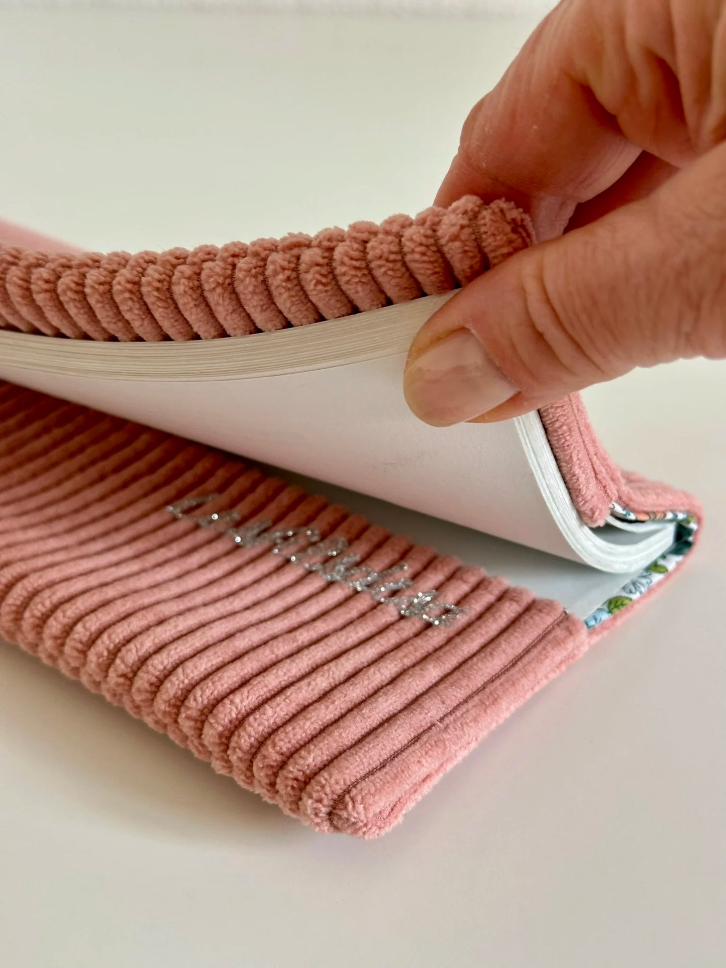 Le rabat inférieur du porte chéquier en velours rose blush.