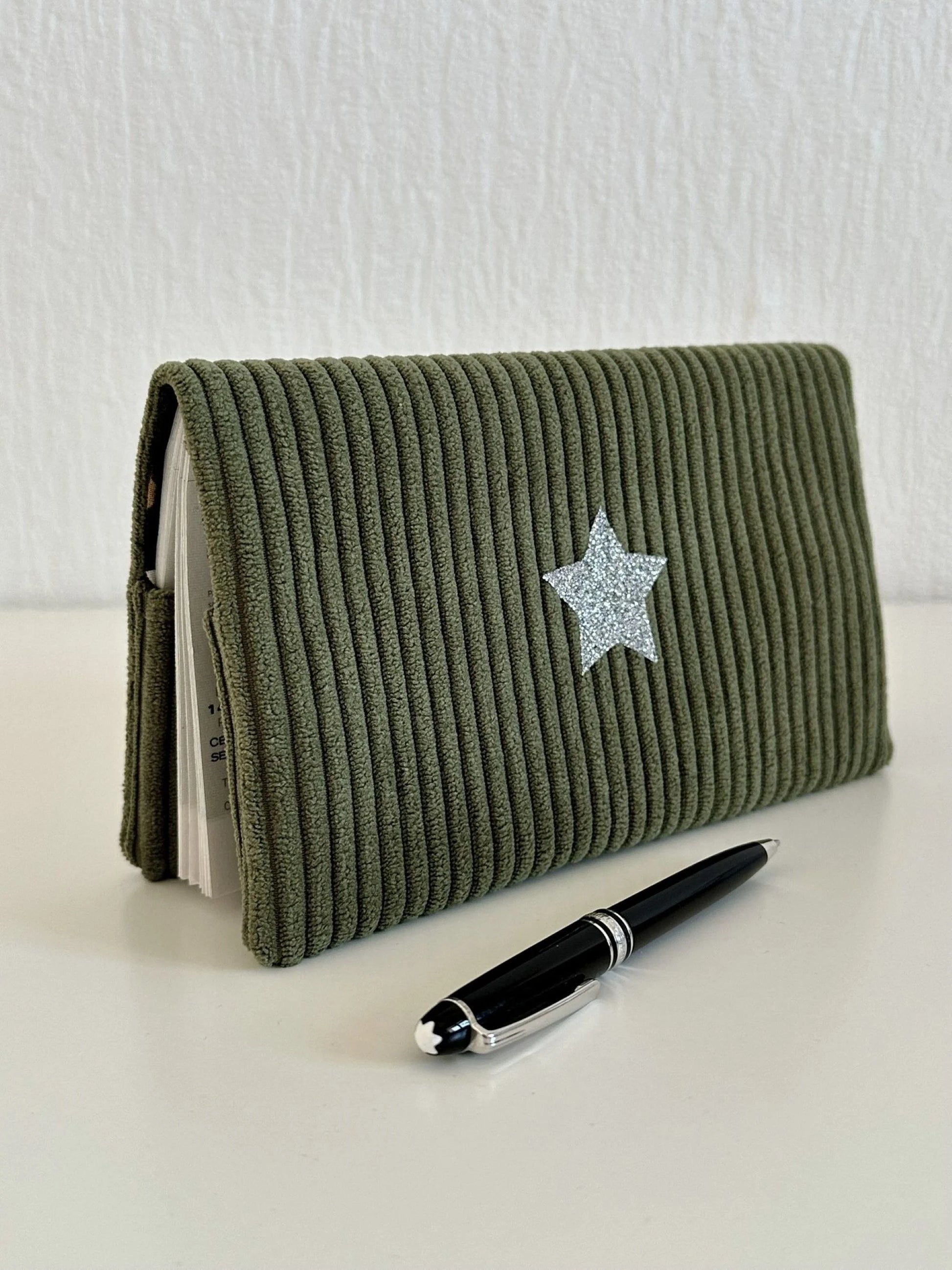 le porte chéquier en velours vert armée et son étoile pailletée argentée en face avant.
