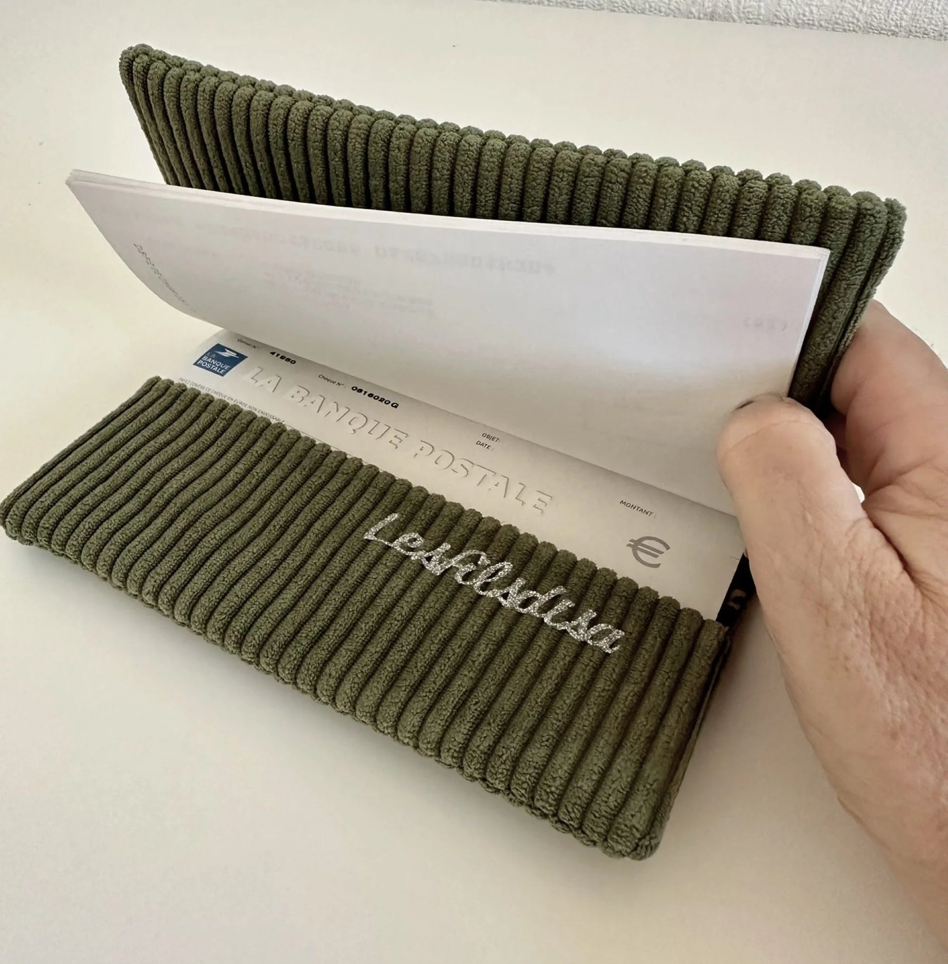 le rabat inférieur du porte chéquier en velours vert armée et son étoile pailletée argentée .