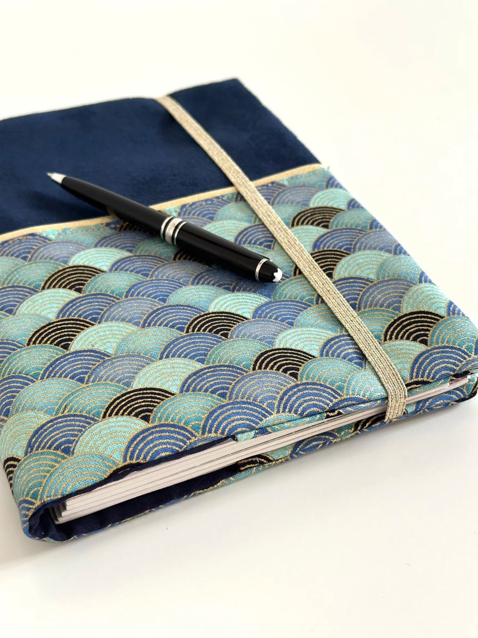 Le protège agenda bleu marine en tissu Seigaiha turquoise, fermé par son élastique doré.