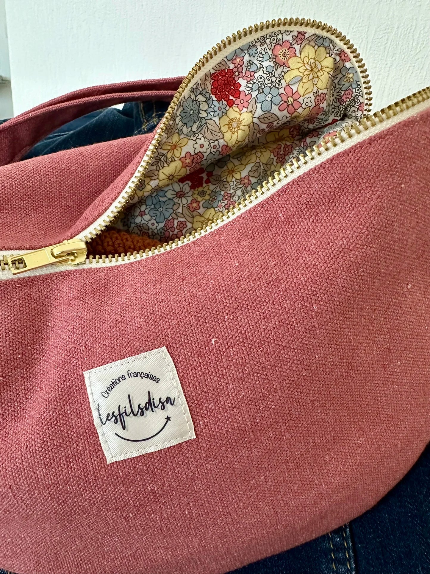 La doublure intérieure fleurie du sac banane en toile framboise, entrouvert.
