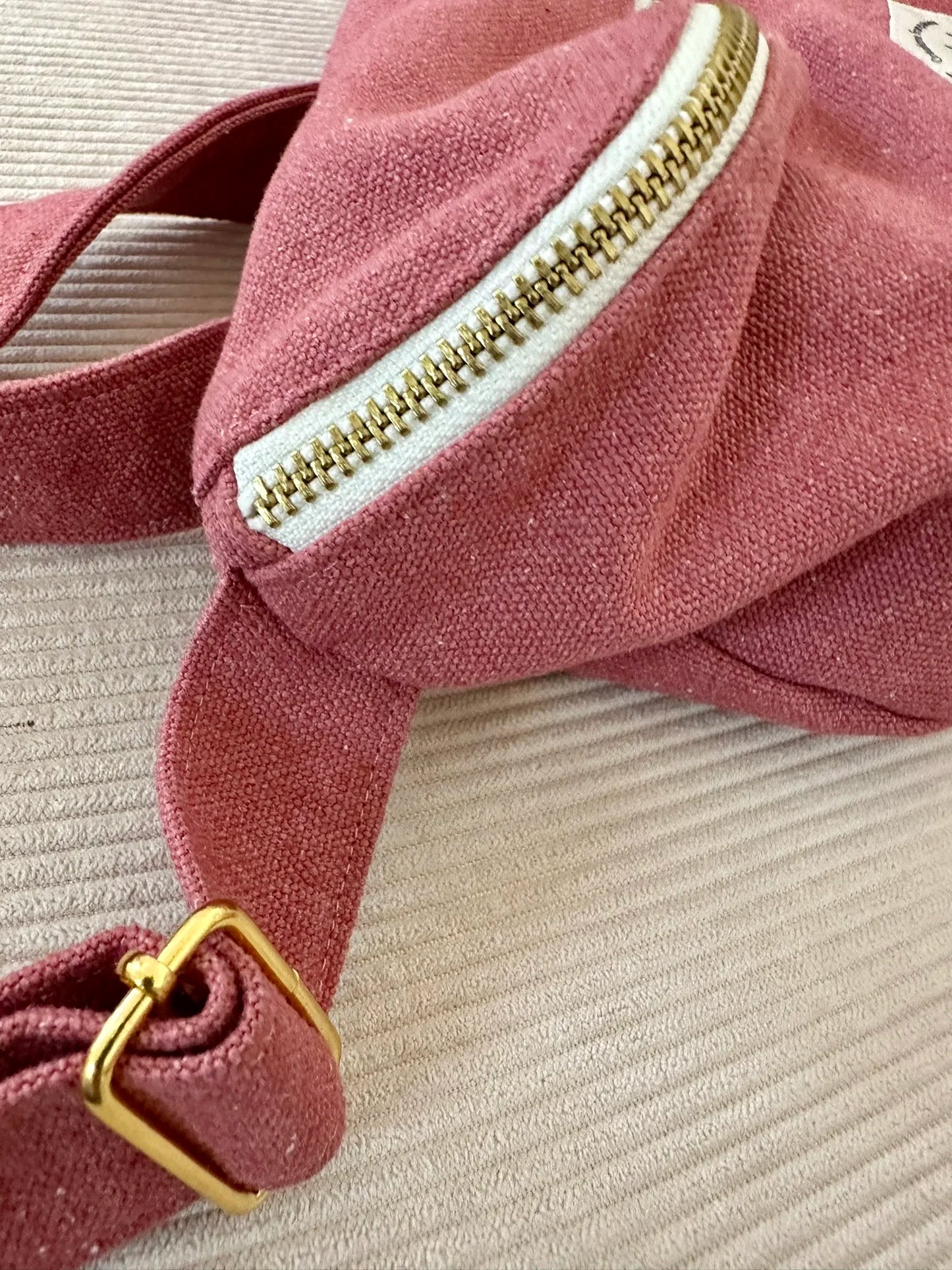 Vue détaillée de la fermeture métallique zippée du sac banane en toile framboise.