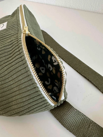Le sac banane en velours cotelé vert armée, entrouvert.