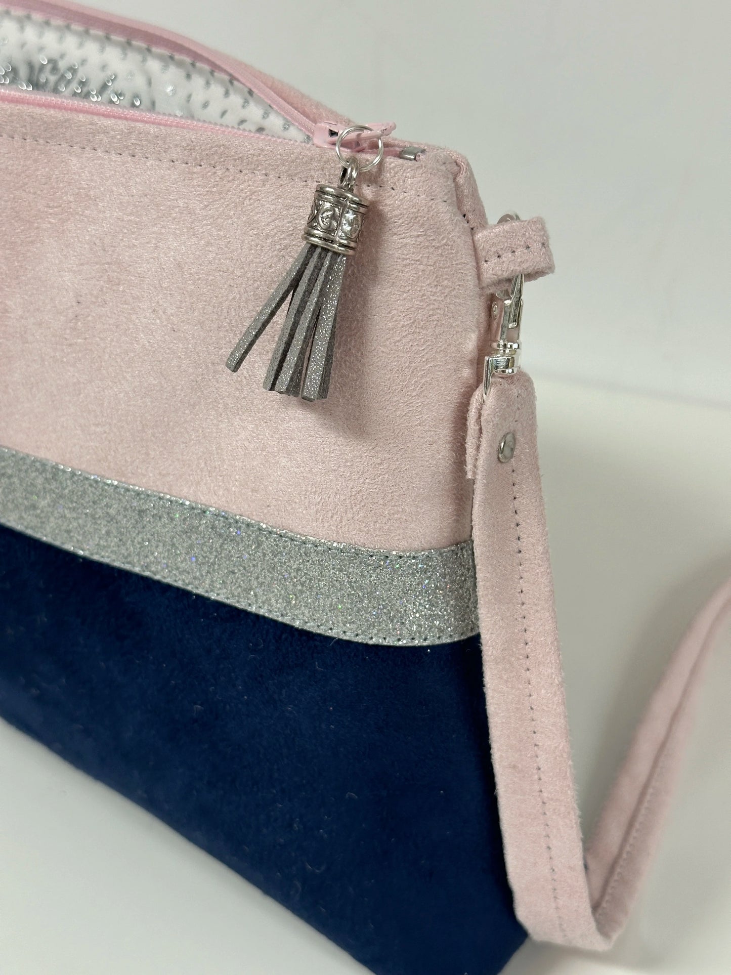 La bandoulière amovible du sac bandoulière rose pale et bleu marine à paillettes argentées.