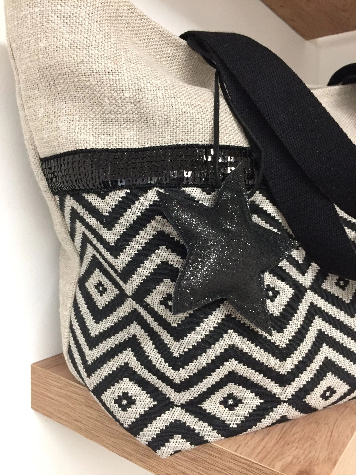 Vue détaillée de l'étoile amovible du sac cabas Isa en lin et chevrons noirs à paillettes.