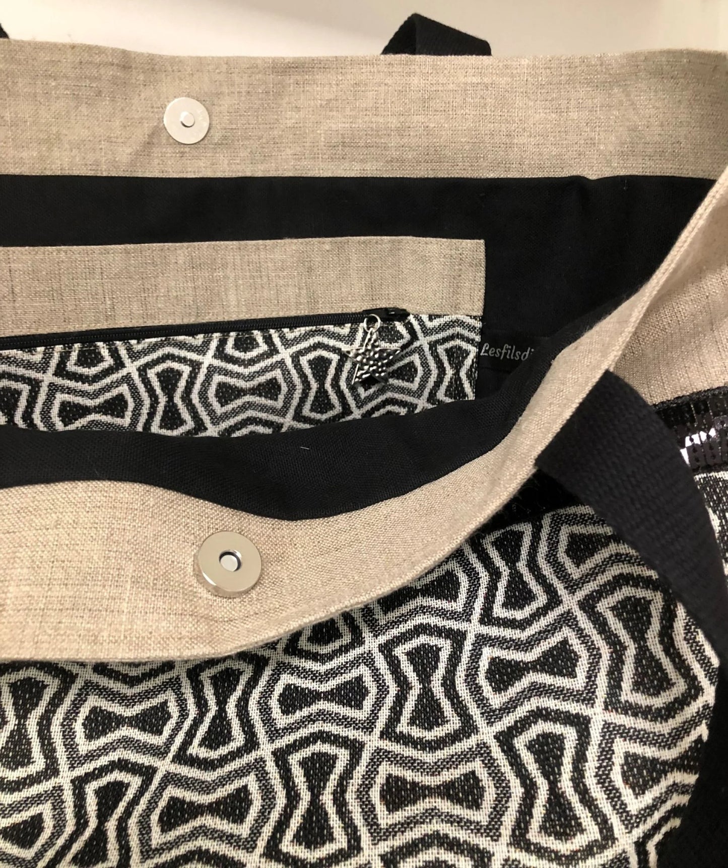 La poche intérieure zippée du sac cabas Isa en lin et tissu jacquard à paillettes noires.