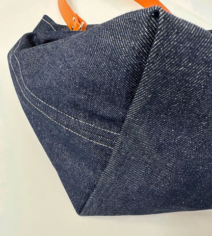 Le fond du sac hobo en denim et son anse en cuir orange .