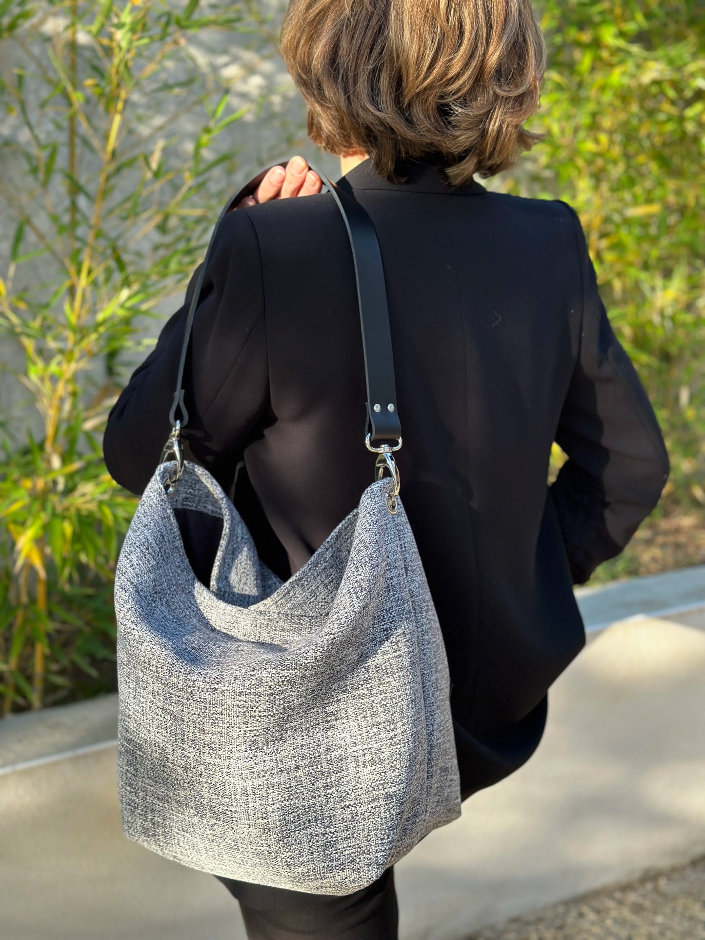 Femme portant le sac hobo gris chiné et son anse en cuir noir.
