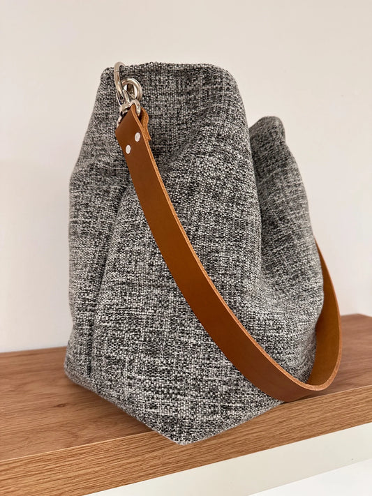 Le sac hobo gris chiné et son anse en cuir fauve.