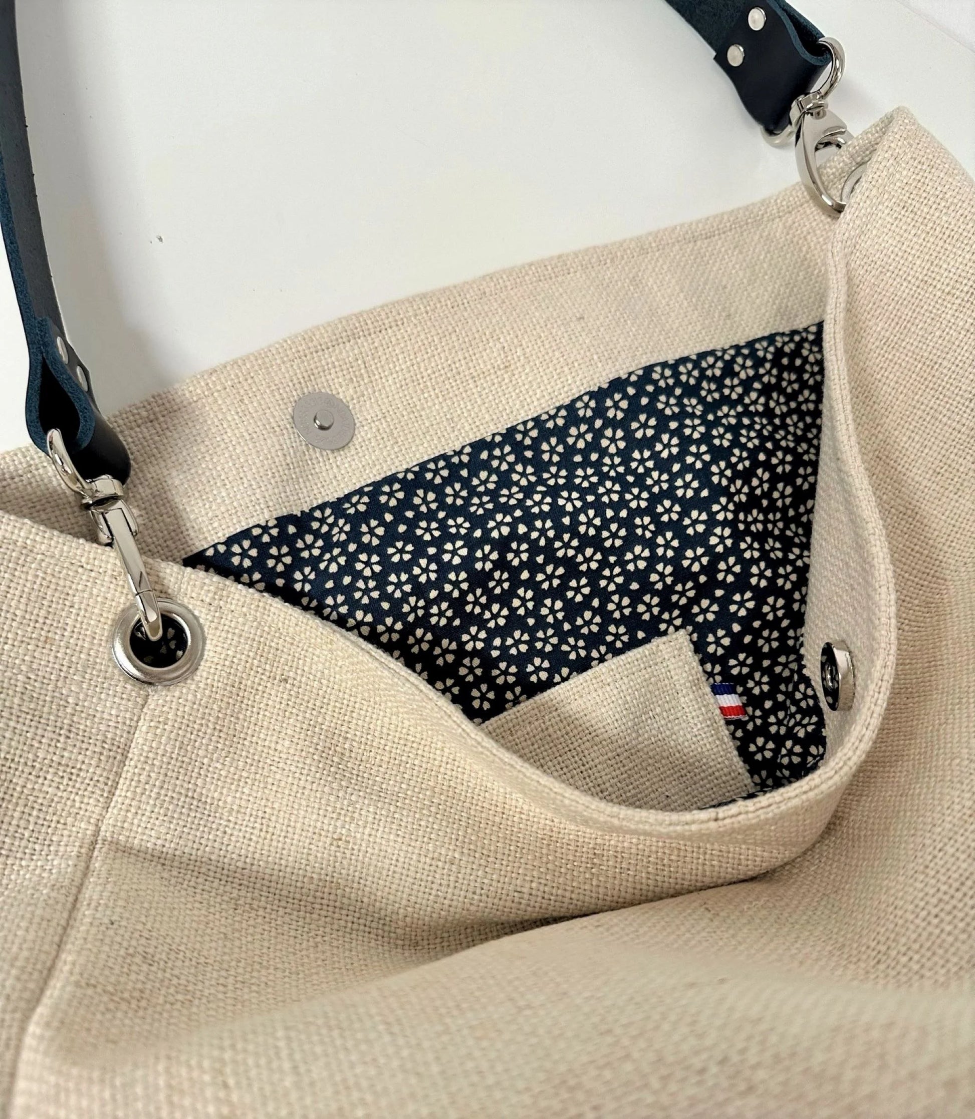 La poche plaquée intérieure du sac Hobo en lin ivoire et anse amovible en cuir bleu.