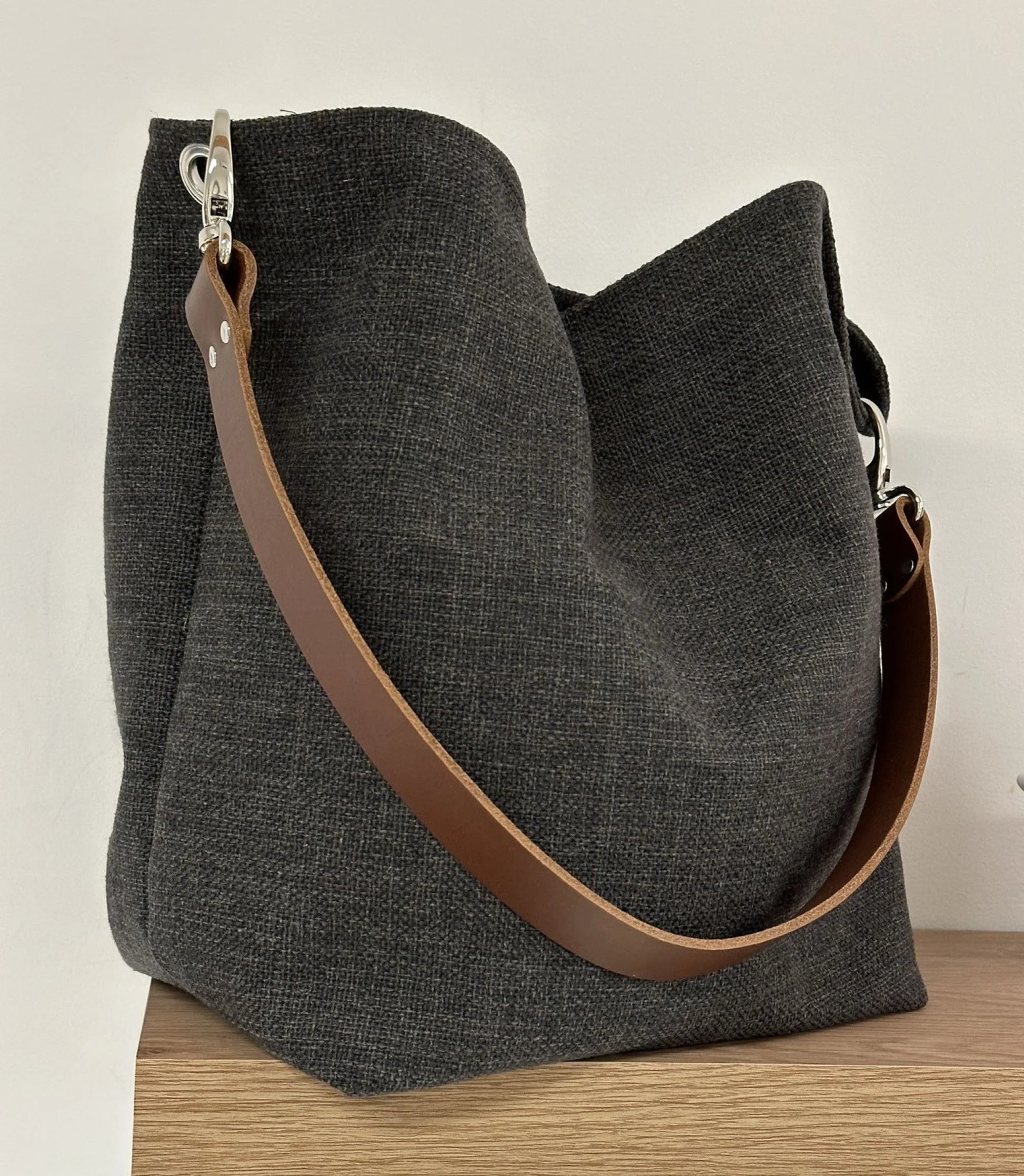 Le sac Hobo en lin anthracite et son anse en cuir marron.