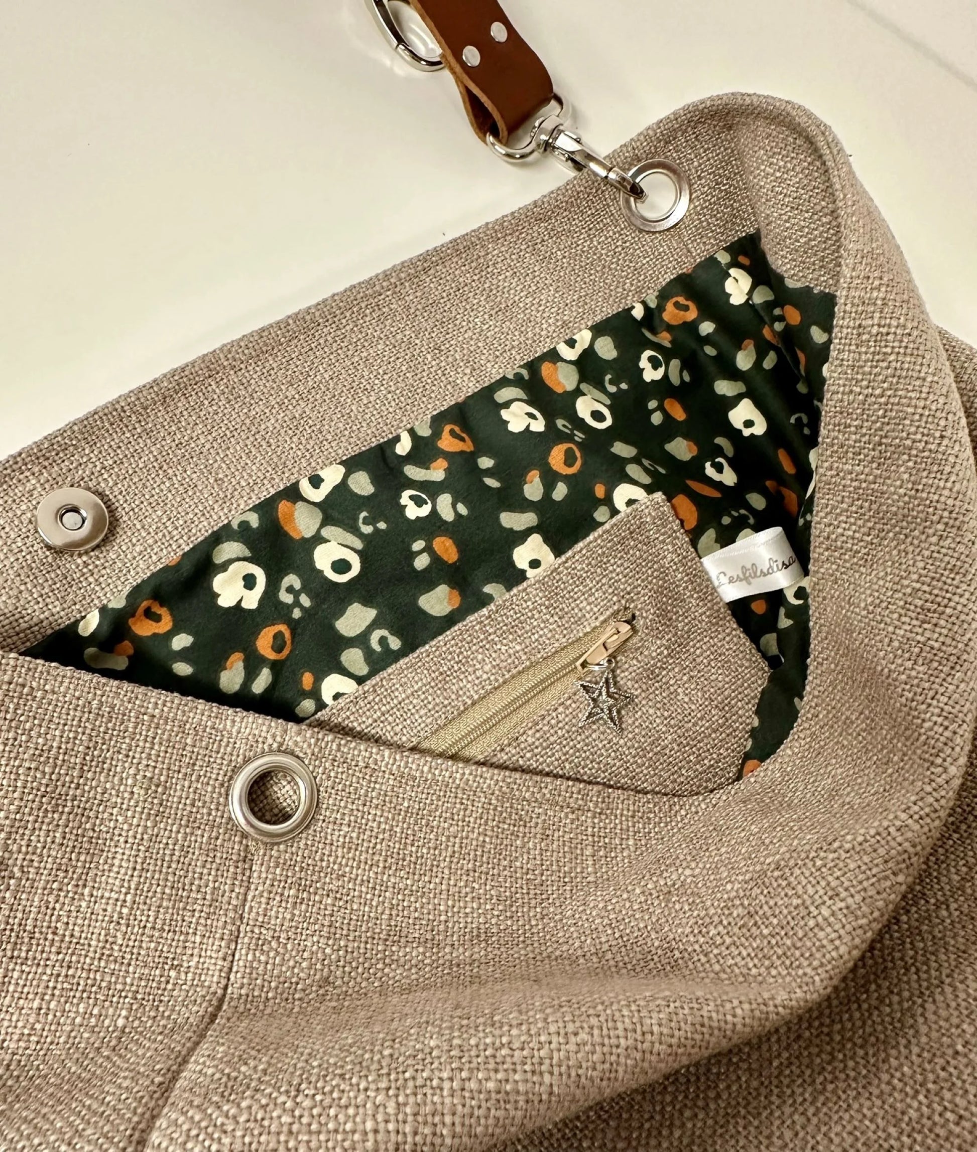 La doublure intérieure avec la poche zippée du sac hobo en lin beige et anse en cuir amovible.