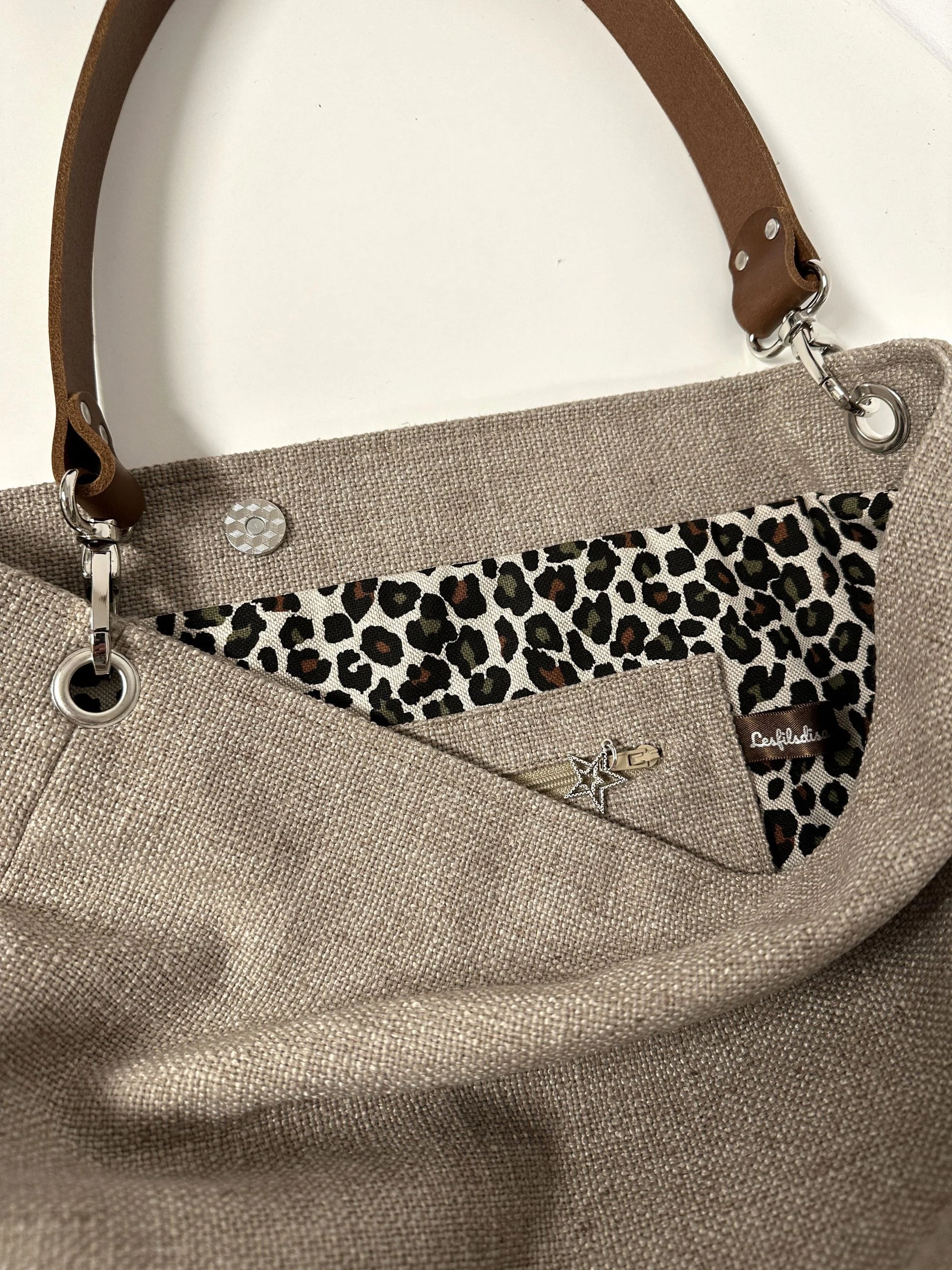 La poche intérieure zippée du sac hobo en lin beige et toile léopard, avec son anse en cuir marron amovible