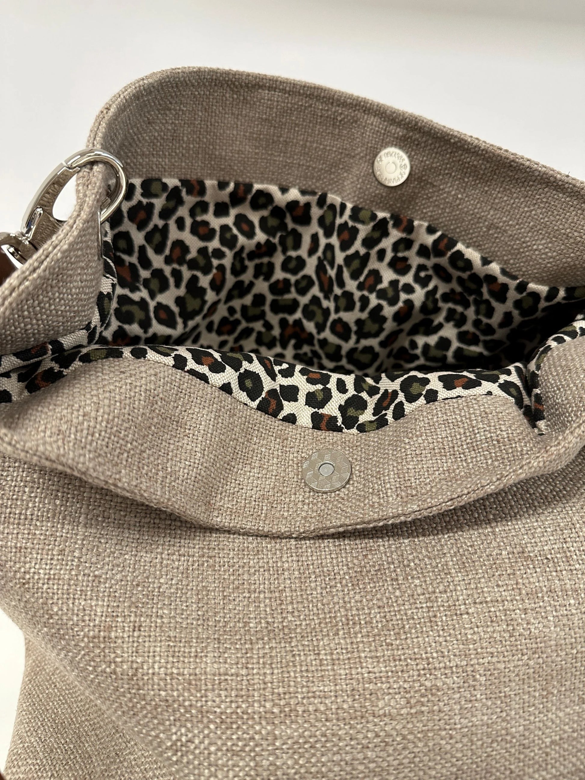 La toile léopard intérieure du sac hobo en lin beige et toile léopard, avec son anse en cuir marron amovible.