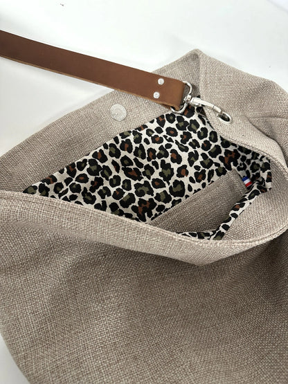 La poche intérieure plaquée du sac hobo en lin beige et toile léopard, avec son anse en cuir marron amovible.