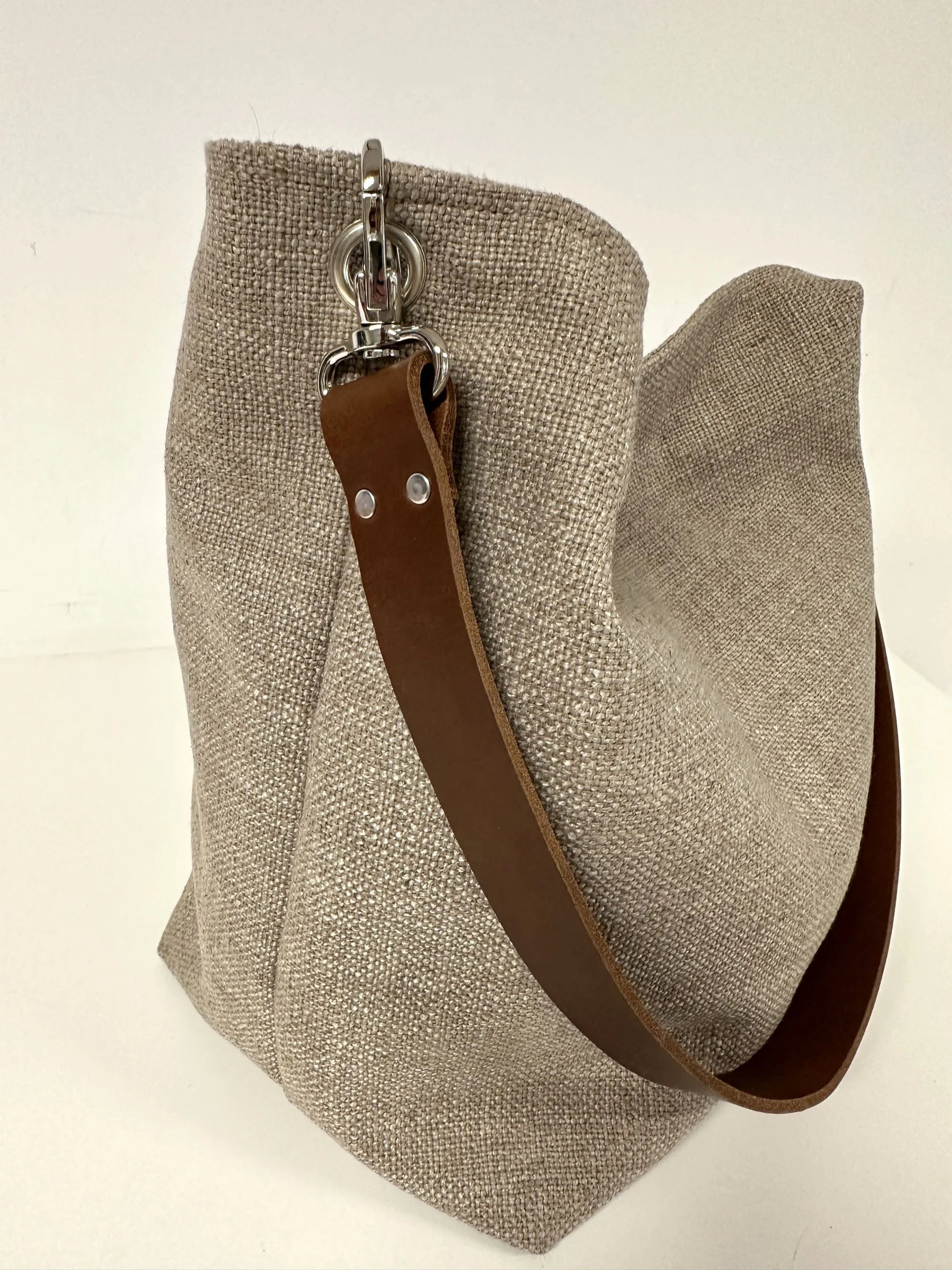 Le sac hobo en lin beige et toiel léopard, avec son anse en cuir marron amovible.