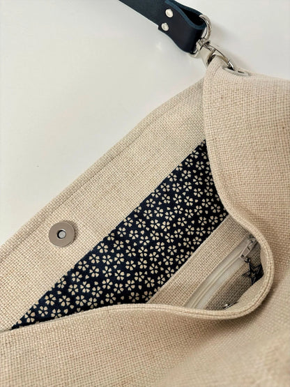La poche intérieure zippée du sac Hobo en lin ivoire et anse amovible en cuir bleu.