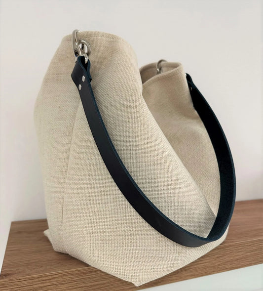 Le sac Hobo en lin ivoire et anse amovible en cuir bleu.